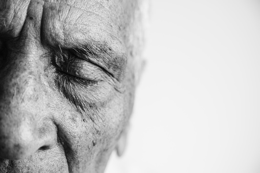 Close up picture of an old man with eyes closed, on white background. Black and white photo.