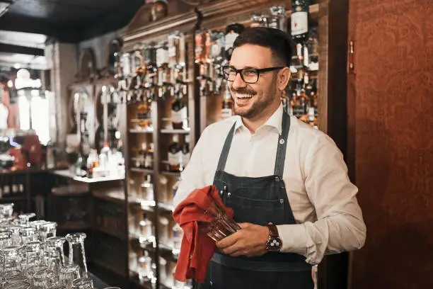 Young male bartender cleaning bar counter