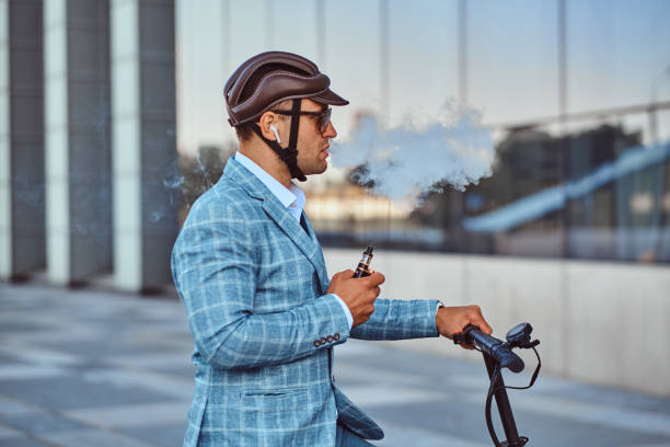 Elegant man with electro scooter is smoking vape