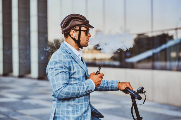 istock Elegant man with electro scooter is smoking vape 1169781379
