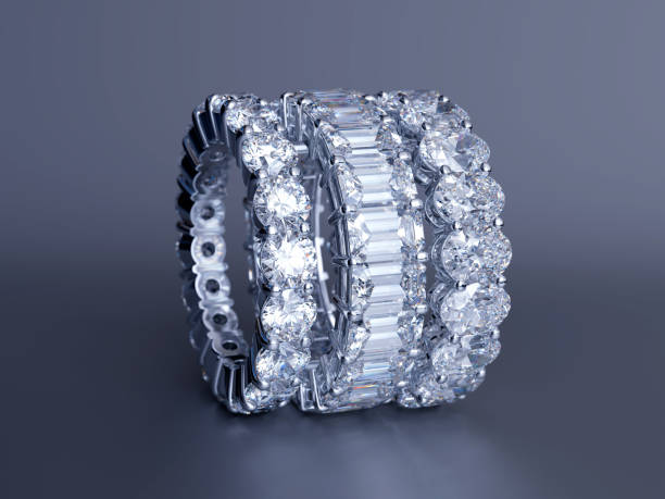 istock Three diamond eternity rings featuring round, emerald, oval cut diamonds,  on gray glossy background 1169783741