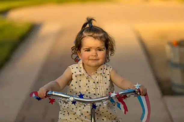 High quality stock photos of a little girl riding a tricycle during a summertime sunset.