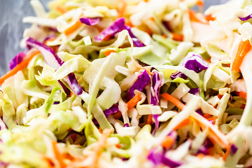 Close up view. Making homemade coleslaw in a glass bowl.