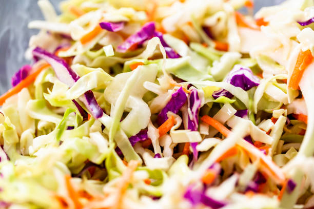 Making homemade coleslaw in a glass bowl. Close up view. Making homemade coleslaw in a glass bowl. coleslaw stock pictures, royalty-free photos & images