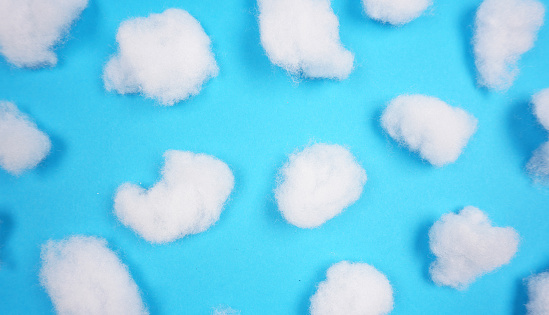 White cotton texture is soft, fluffy wadding at blue background (winter clouds, abstract)