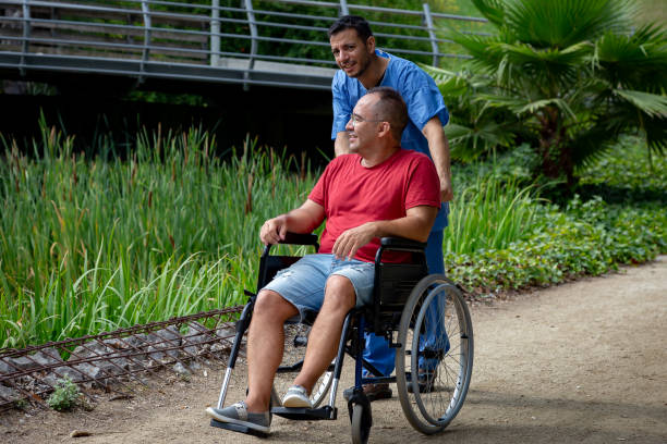 istock disabled man in a wheelchair talking with his caretaker 1169794103