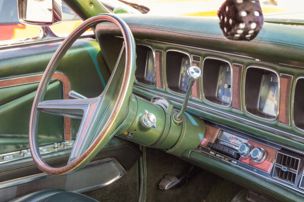 Green leather, wood and chrome interior of a classic american luxury oldtimer car. Steering wheel, radio, speedometer and a hairy dice Green leather, wood and chrome interior of a classic american luxury oldtimer car. Steering wheel, radio, speedometer and a hairy dice. 1970 retro styled imagery stock pictures, royalty-free photos & images