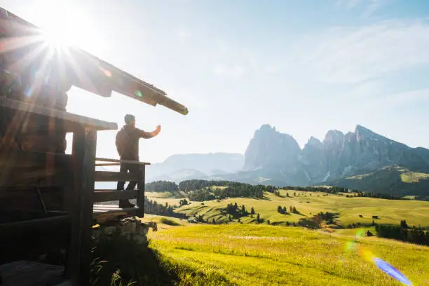 Photo of Young man enjoys view of mountains from balcony of a cabin