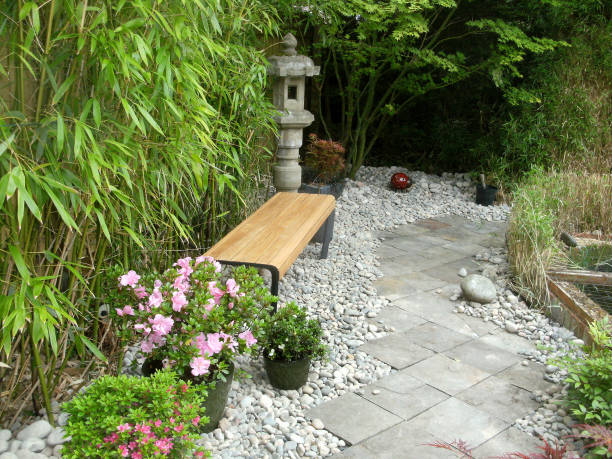 immagine di sentiero di lastra di ardesia in ornato, giardino domestico con elementi giapponesi, moderna panchina in legno, azalee in vaso, lanterne di granito, copertura di bambù, stagno di pesce koi e aceri giapponesi (acers) - nature japanese garden formal garden ornamental garden foto e immagini stock