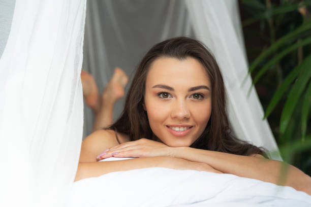 Charming young woman lying down on bed and smiling