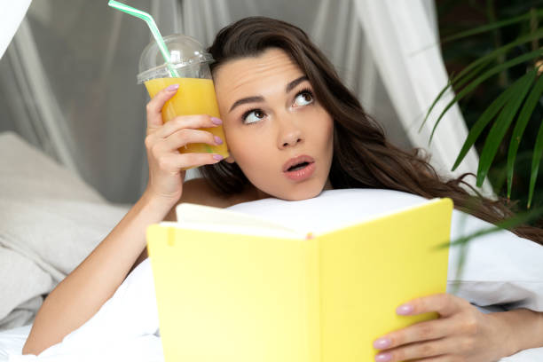 istock Charming young woman reading book and holding cocktail 1169804708