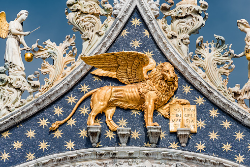 Golden winged lion with parchment as roof decoration of Basilica San Marco in Venice, Italy