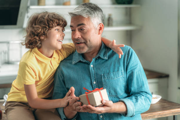 istock Son gives father small present box at home 1169808706
