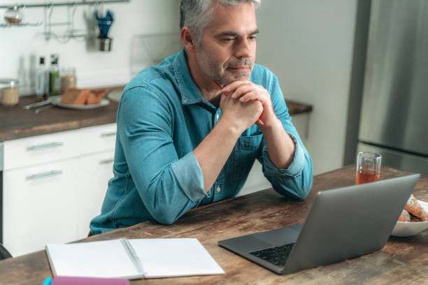 istock Mature man looking on display and working with laptop 1169808755