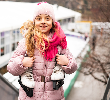 Portrait beautiful girl after ice skating standing near ice rink and smiling