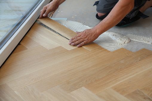 Trabajador coloca suelo de parquet. Trabajador instalando pisos laminados de madera photo