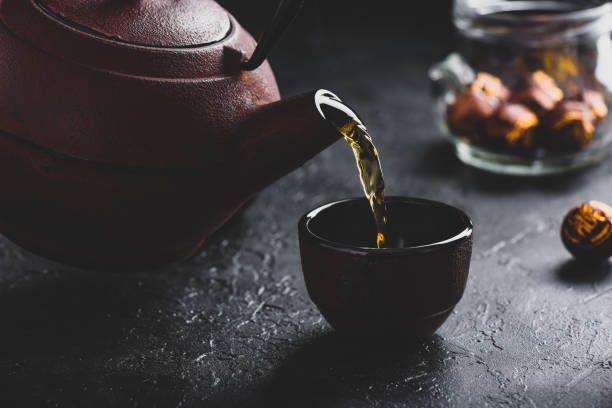 verser le thé rouge prêt dans le cuvette de thé - tea cup cup shape red photos et images de collection