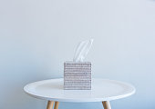 Tissue box on small white table against wall