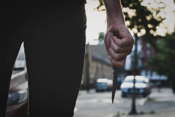 un ladrón o un asesino con un cuchillo afilado en la calle antes de la oscuridad. concepto de robo del crimen - cuchillo arma fotografías e imágenes de stock