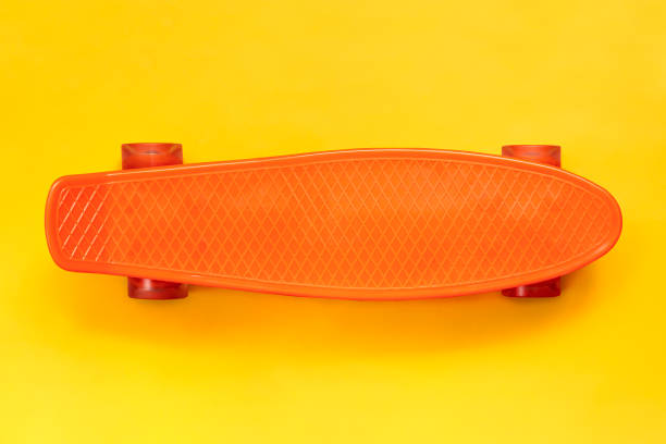 istock Orange cruiser skateboard deck on yellow background. view from above 1169834775