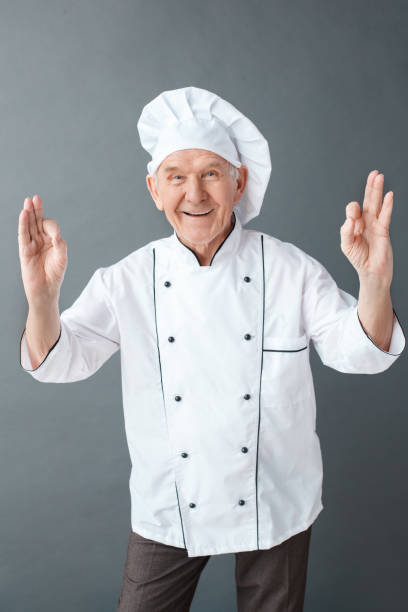 istock Senior chef studio standing isolated on gray smiling cheerful showing ok sign 1169834945