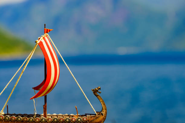 Old wooden viking longboat sails, drakkar boat on fjord shore in Norway. Tourism and traveling concept