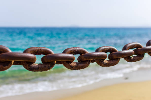 Thick rusty chains with the sea in the background