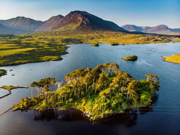 Aerial view of Twelve Pines Island, standing on a gorgeous background formed by the sharp peaks of a mountain range called Twelve Pins or Twelve Bens, Connemara, County Galway, Ireland