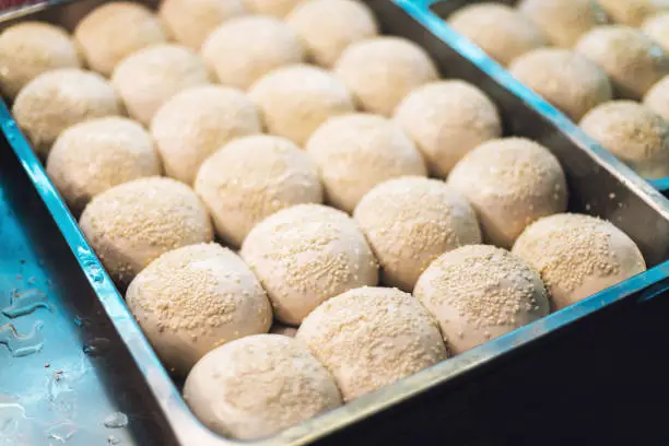 Photo of Sheng Jian Bao: White pork bun topping with sesame before fry. Street food of Jiantan in Taipei, Taiwan.