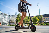 e-mobility commute to work, businesswoman on electric push scooter in city