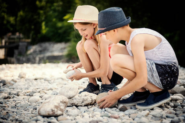 Brother and sister stacking stones at the river