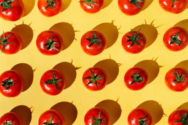 istock Flatlay of fresh red ripe tomatoes arranged on yellow background 1169868410