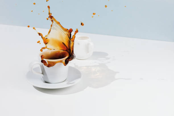 istock Cup with splashing coffee, saucer and creamer on white table 1169868411