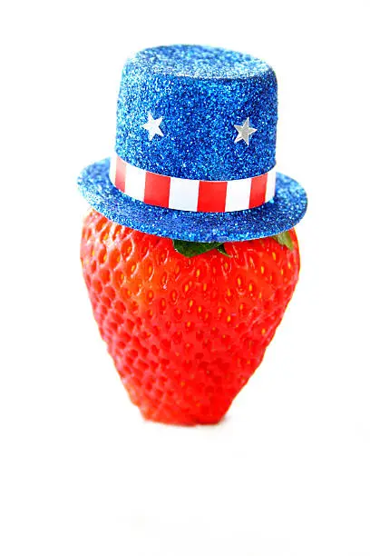 a strawberry with a fourth of July top hat on, all isolated on a white background.  Selective focus on the hat.
