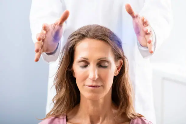 Close-up Of A Therapist Hand Giving Reiki Healing Treatment To Woman In Spa