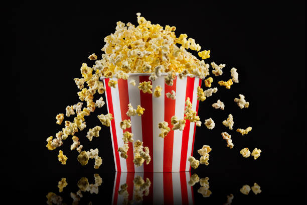 istock Flying popcorn from striped bucket isolated on black background 1169875731