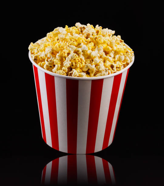 istock Paper striped bucket with popcorn isolated on black background 1169875895