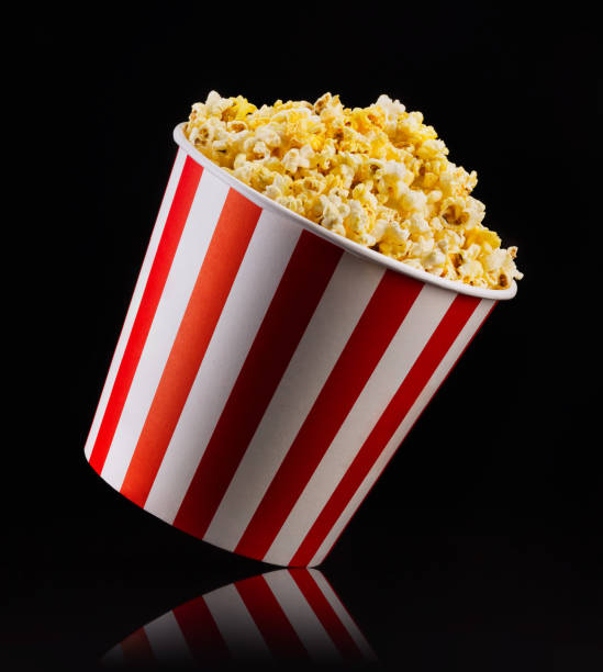 istock Paper striped bucket with popcorn isolated on black background 1169875929