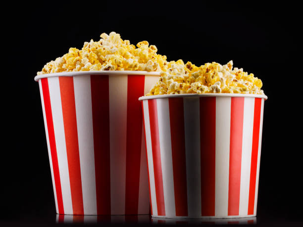 istock Paper striped buckets with popcorn isolated on black background 1169875959