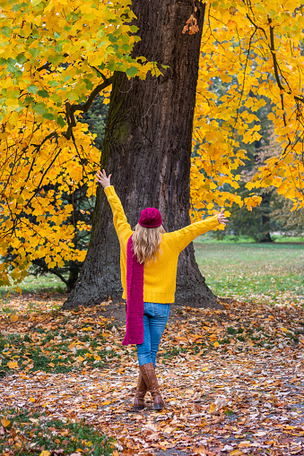 Happy fashion woman enjoying autumn at park. Trendy casual clothing