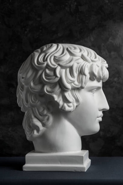 istock Gypsum copy of ancient statue Antinous head on dark textured background. Plaster sculpture man face. 1169876607