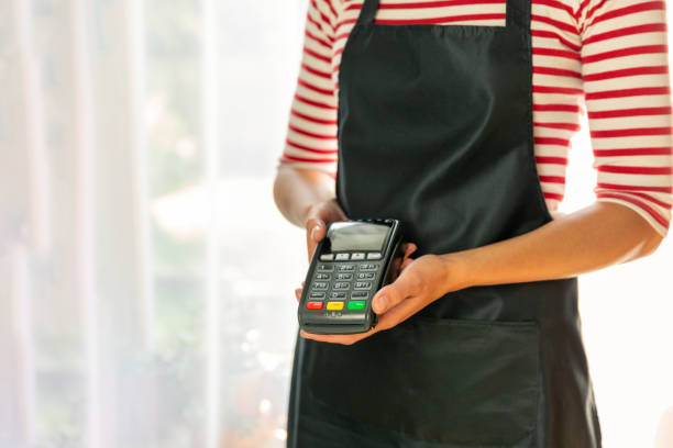 istock Store worker requesting for payment over nfc technology. Store worker holding pos terminal 1169890490