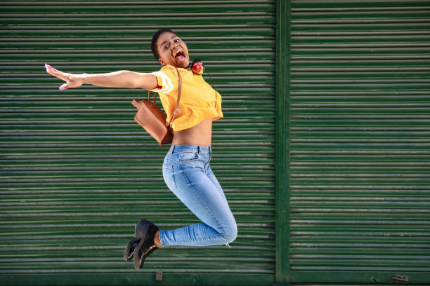 istock Young black woman jumping on blinds background. 1169891337