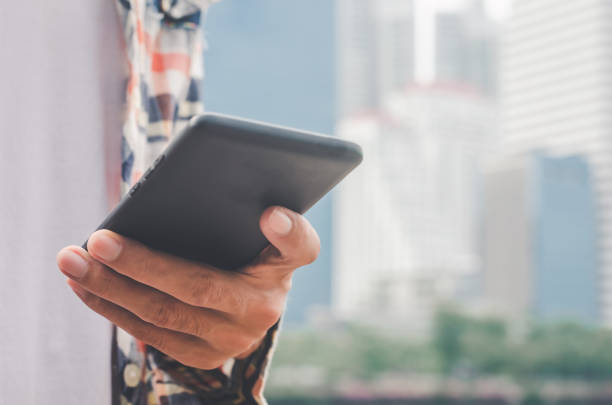 istock close up handsome man using hand typing mobile phones and touch screen working search with app devices outdoor in city with sunrise and building background. 5G technology connecting the world. 1169893687