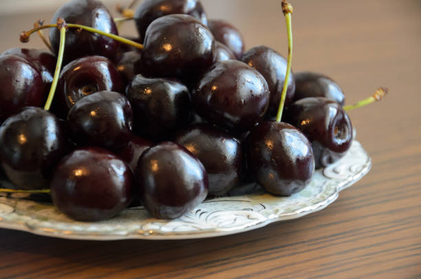 istock Wet chilled cherries with peduncles on saucer on table 1169895453