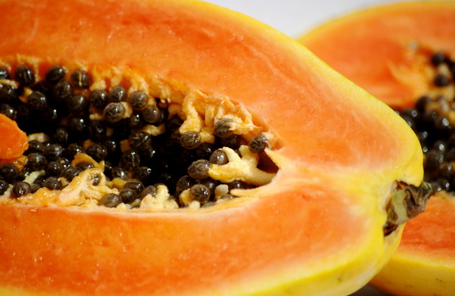 A closeup of a papaya cut in half isolated on a white background