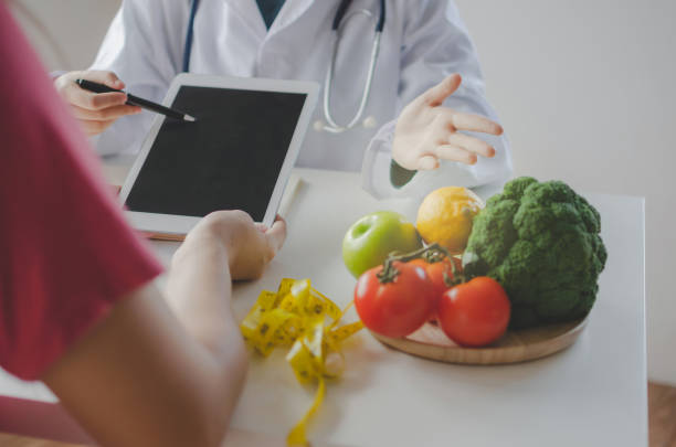 istock friendly nutritionist female doctor or medical using tablet and talking about diet plan with patient on desk at laboratory room at office hospital, food science, healthy food and dieting concept 1169899346