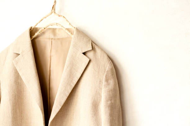 istock beige jacket hanging on clothes hanger on white background. 1169899496