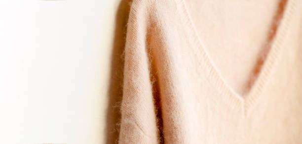 istock light pink sweater hanging on clothes hanger on white background. 1169899584