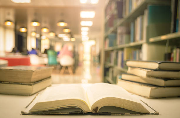 öffnen sie lehrbücher auf dem lesepult im verschwommenen bibliotheksraumhintergrund - professor librarian university library stock-fotos und bilder